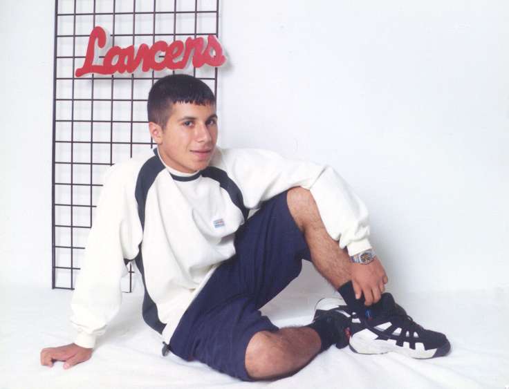 Farid - Full body shot - sitting in front of Lancer sign.