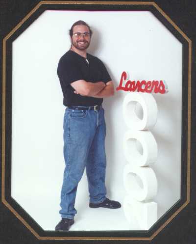 Phillip in his normal school wear, black t-shirt and blue jeans wiht lancer sign and 2000 sign.
