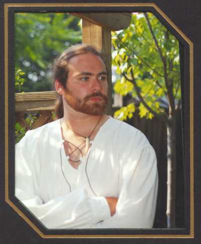 Phillip outside with porch background in white medieval shirt.