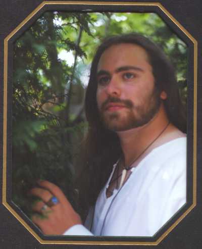 Phillip outside with tree background in white medieval shirt.